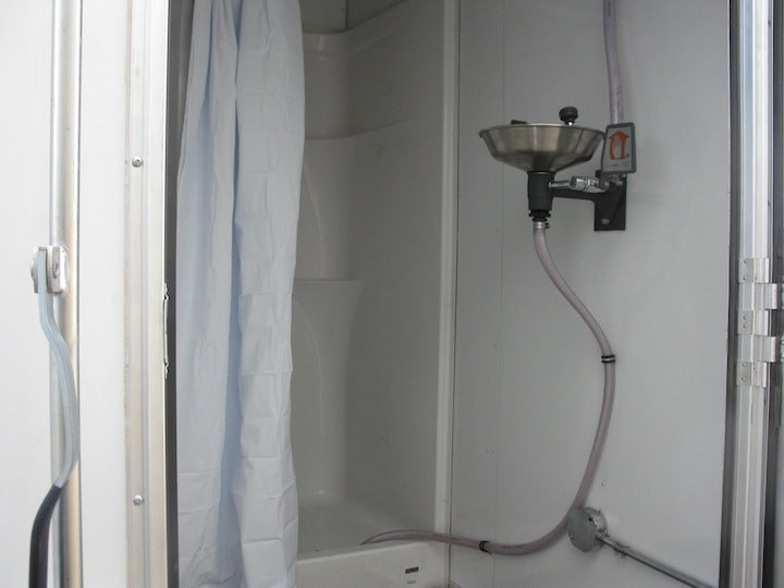 Shower stall with a shower head and hose in a compact bathroom setting.