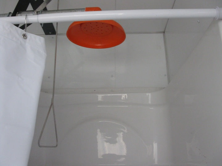 Orange shower head attached to a white pipe in a bathroom setting