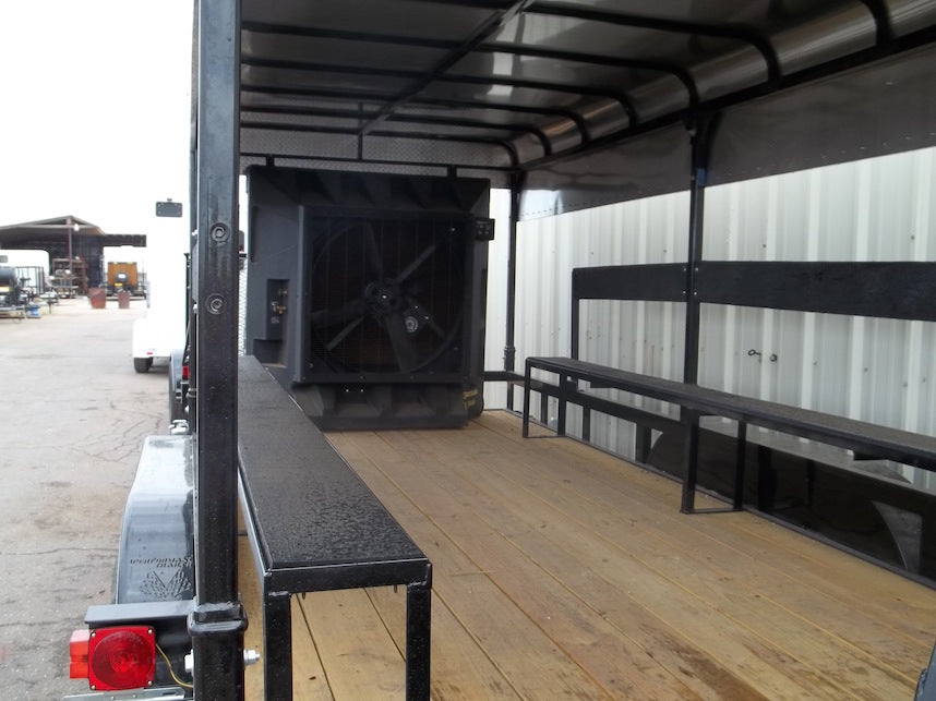 Trailer interior with benches and a large black object on a wooden floor.