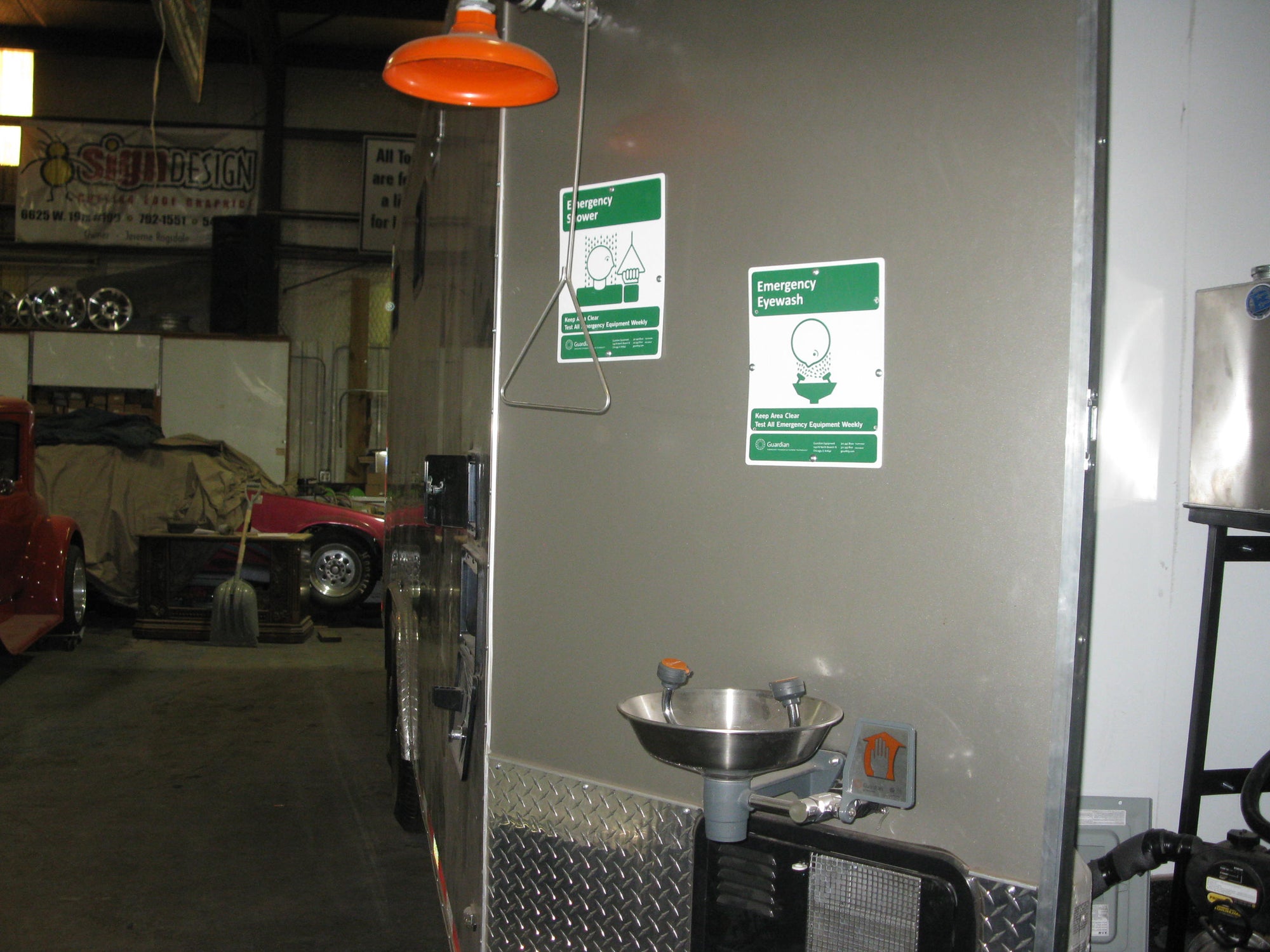 Metal sink with water faucet inside a vehicle or trailer, with safety signs on the wall.